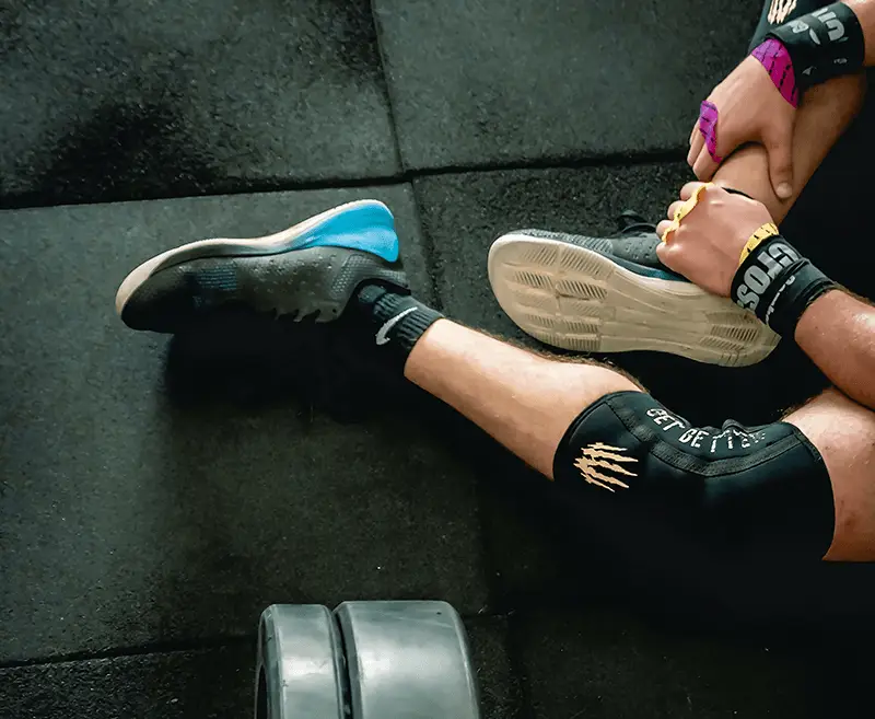 Image of a weightlifter adjusting their shoe during a training session