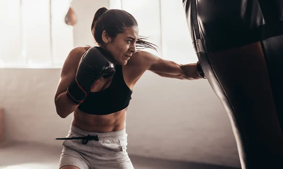 Woman during boxing training sparring on a boxing bag in a gym