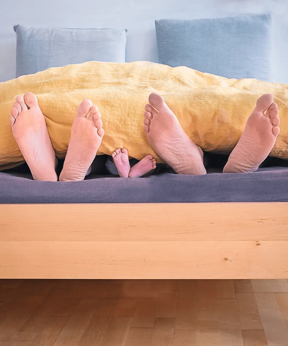 Image of a family in bed with their feet hanging out of the quilt cover