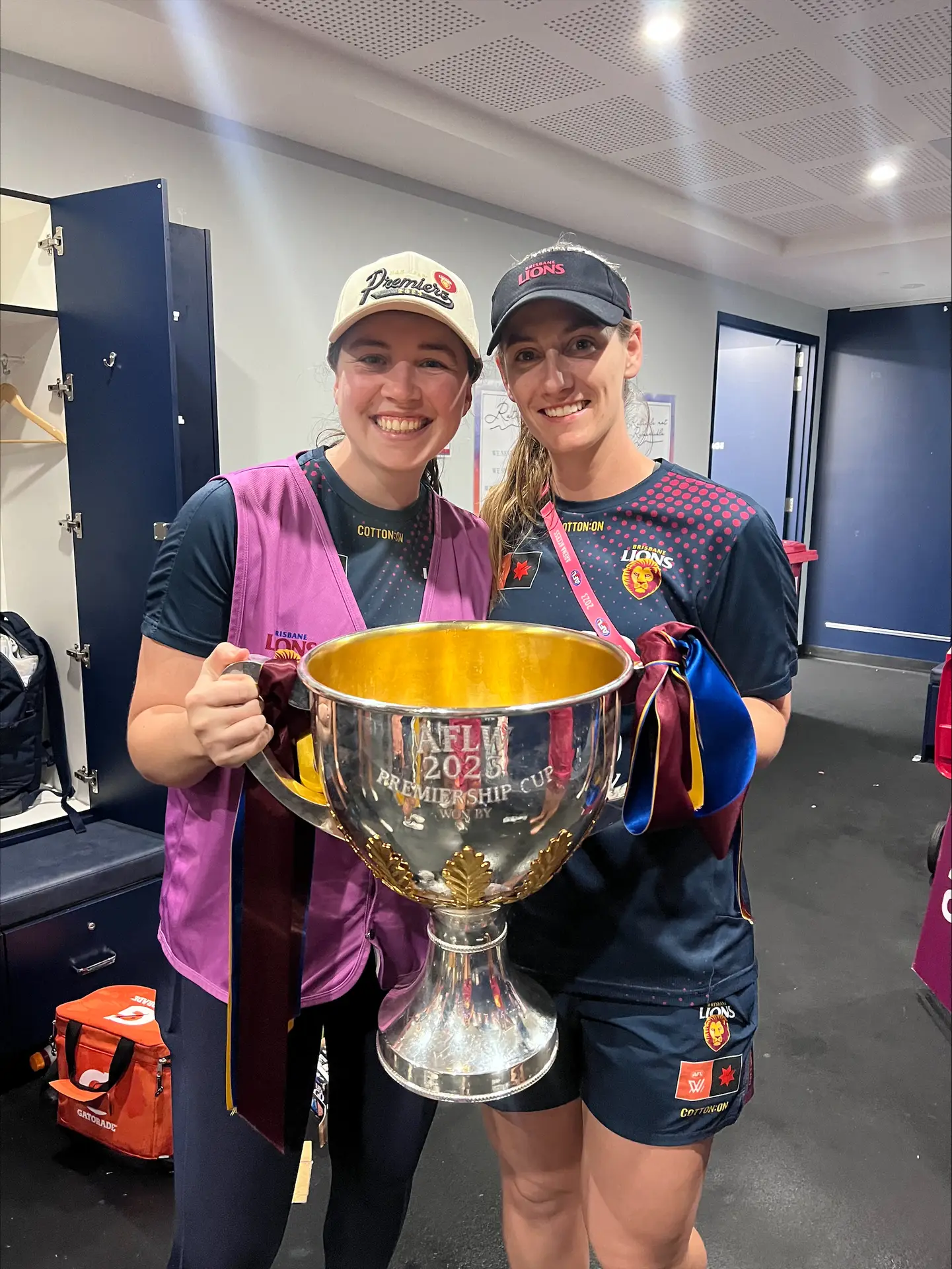 QSMC Physiotherapists Abbey Le Busque and Jess Clarey pictured with the AFL Premiership Cup after the Brisbane Lions' 2024 Premiership-winning season.