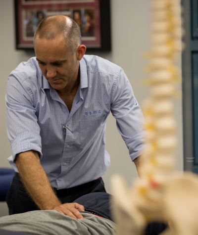 Headshot of Physiotherapist and QSMC Director Shane Lemcke treating in clinic.